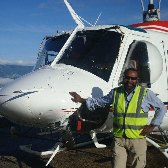 Graduate David Takendu next to a helicopter